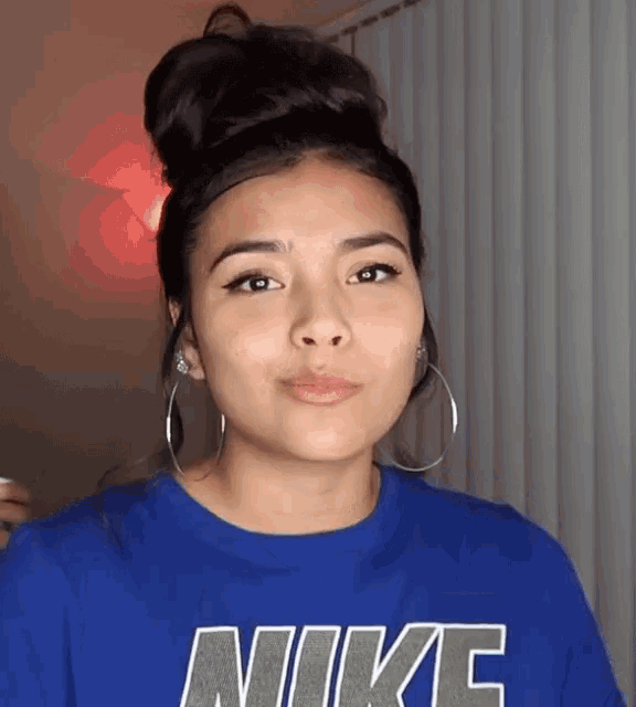 a woman wearing a blue nike shirt with hoop earrings