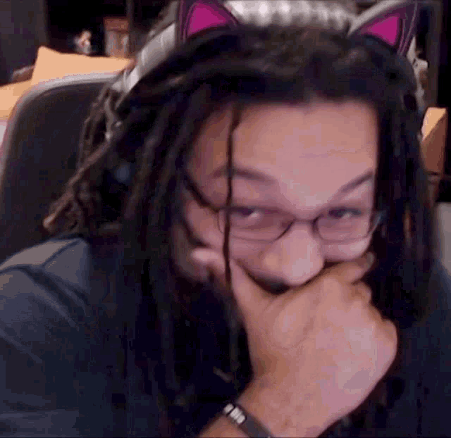 a man with dreadlocks and glasses is wearing cat ears .