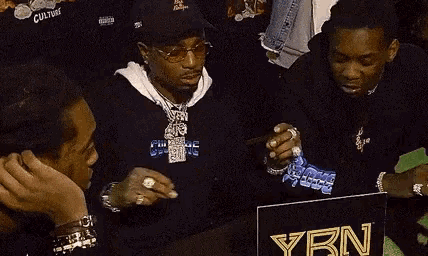 a group of men are sitting in front of a sign that says ybn on it .