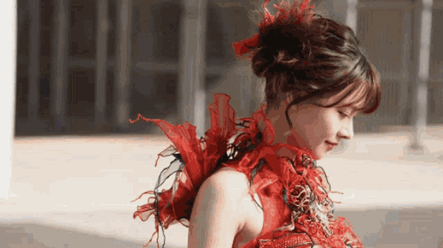 a woman in a red dress with feathers in her hair looks down