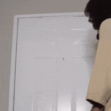 a woman stands in front of a white door smiling