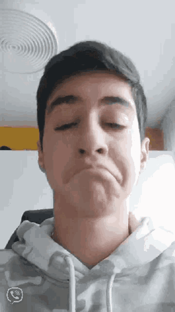 a young man making a funny face with his eyes closed and a smiley face in the corner