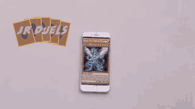 a cell phone with a hole in the screen and jr duels cards behind it