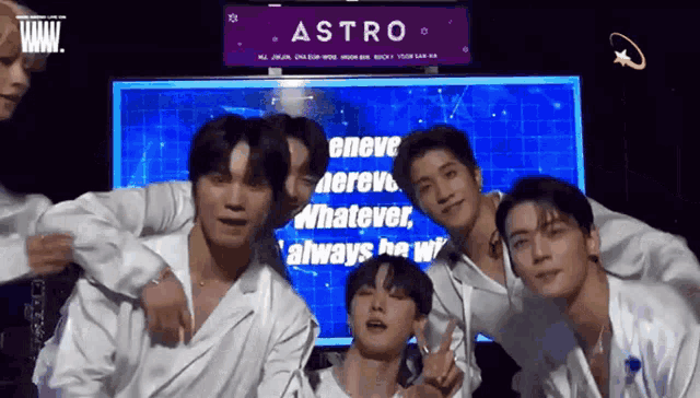 a group of young men posing for a picture in front of a sign that says astro