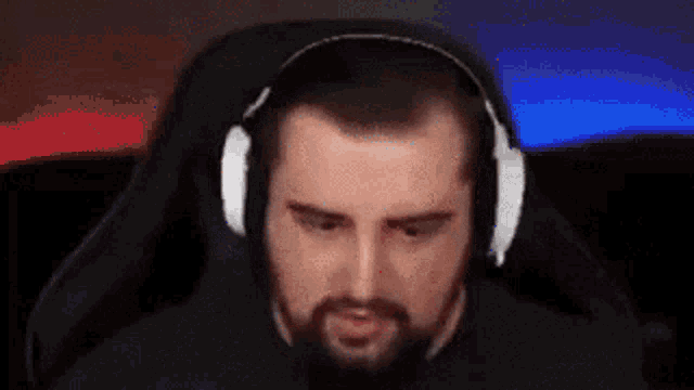 a man with a beard is wearing headphones while sitting in a gaming chair .