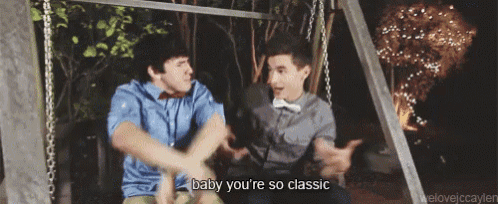 two young men are sitting on a swing and one of them is saying baby you 're so classic