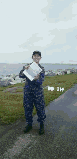 a man in a military uniform is holding a piece of paper with the number 214 on the bottom