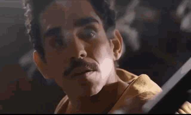 a close up of a man with a mustache looking at something .