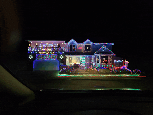 a house is decorated with lots of christmas lights and a sign that says ' christmas ' on it