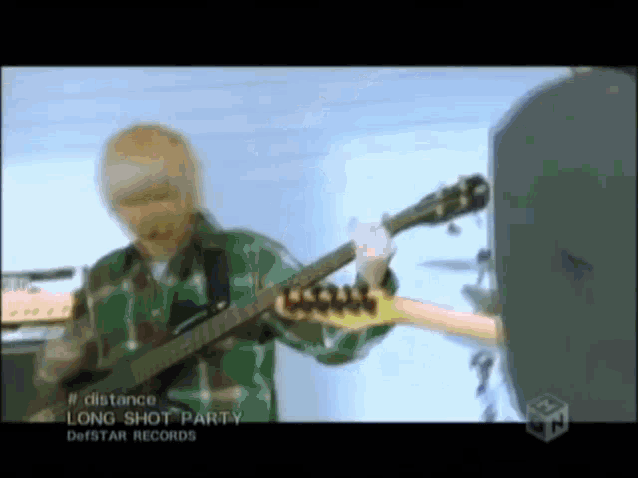 a man in a green plaid shirt is playing a guitar in a video for long shot party