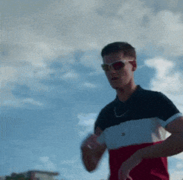 a man wearing sunglasses and a tommy hilfiger t-shirt is running