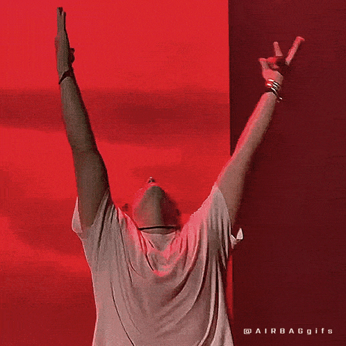 a man in a white shirt is standing with his arms up in the air