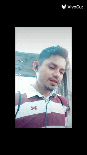 a man wearing a red and white under armour shirt with ear buds