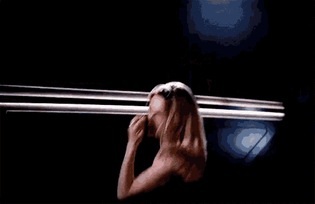 a woman in a black tank top is standing in the dark looking at the camera .