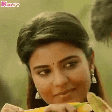 a woman is eating corn on the cob and smiling while looking at the camera .