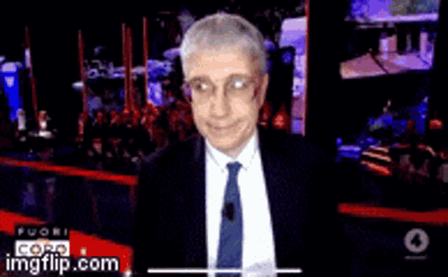 a man in a suit and tie is smiling in front of a screen that says cora imgflip.com