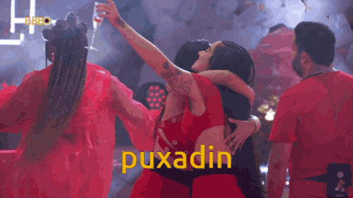 a woman in a red dress is hugging a man in a red shirt and the word puxadin is on the bottom
