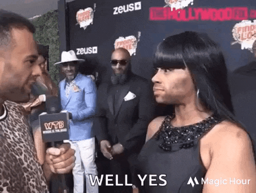 a man is talking to a woman on a red carpet .
