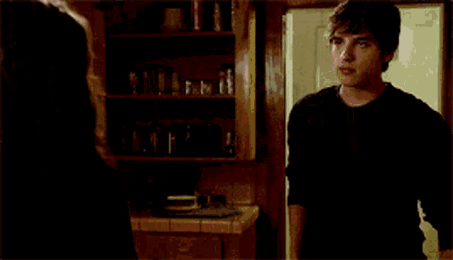 a man and a woman are looking at each other with an exit sign in the background