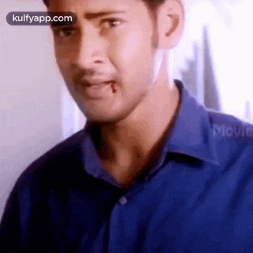 a man in a blue shirt with a bite taken out of his lip is making a funny face .