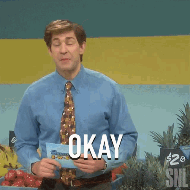 a man in a blue shirt and tie holds a piece of paper that says okay