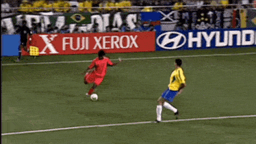 a soccer player kicks the ball in front of a fuji xerox sign