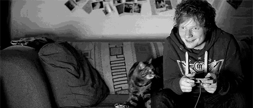 a man is sitting on a couch playing a video game with his cat .