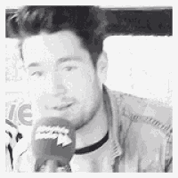 a black and white photo of a man holding a microphone in his hand .