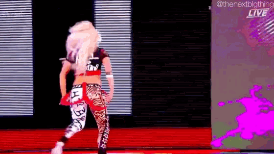 a female wrestler is dancing on a stage in front of a large screen .
