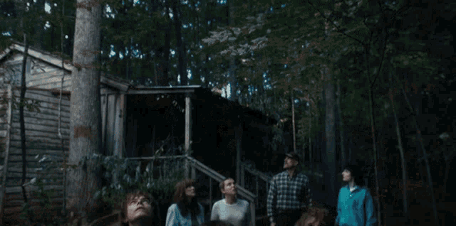 a group of people are standing in the woods looking up