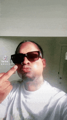a man wearing sunglasses is making a funny face and giving the middle finger