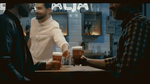 three men are toasting with beer in front of a sign that says alia