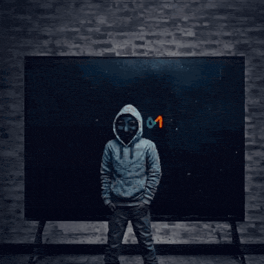 a man wearing a mask stands in front of a large tv