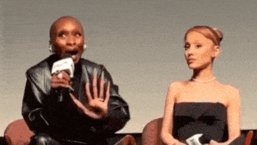 a woman is talking into a microphone while another woman sits next to her .