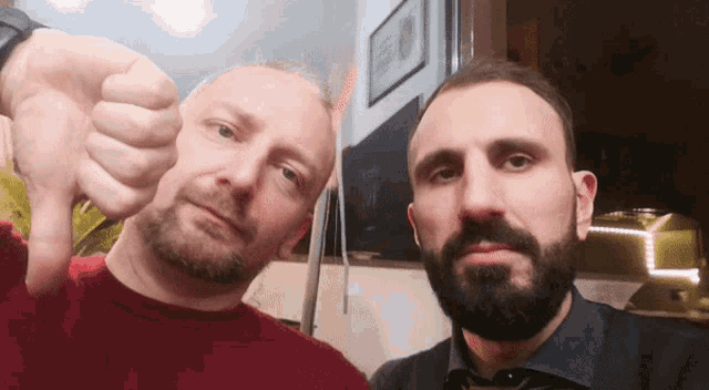 a man with a beard is giving the thumbs down sign
