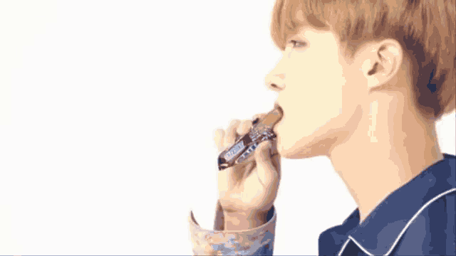 a young man is eating a snickers bar with his mouth .