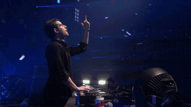 a man in a black shirt stands in front of a pioneer dj mixer