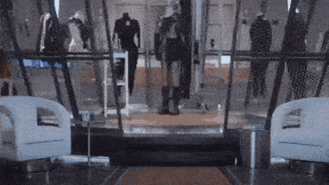 a blurred image of a mannequin in a store with chairs in front of it