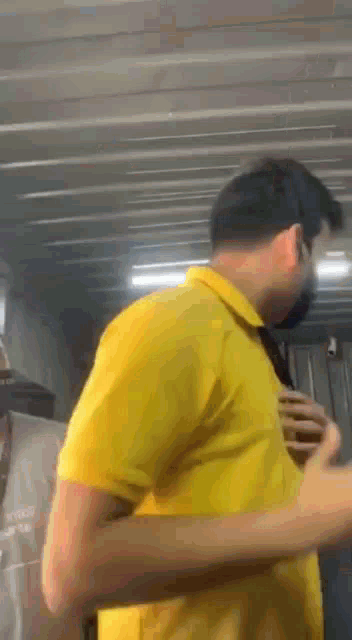 a man wearing a yellow shirt and a mask