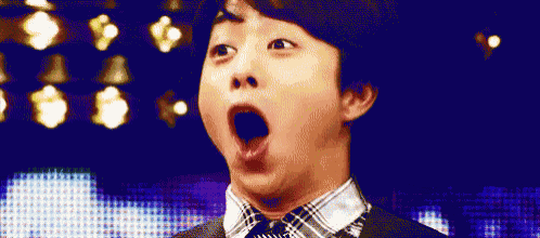 a man in a suit and tie is making a funny face with his mouth wide open .