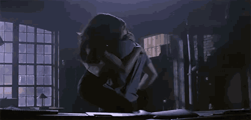 a man and a woman are dancing in a dark room