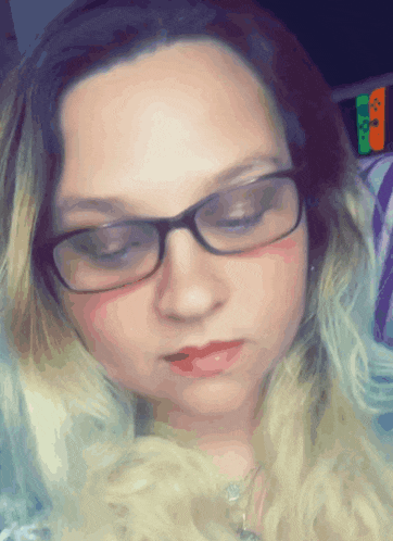 a woman wearing glasses and red lipstick looks down