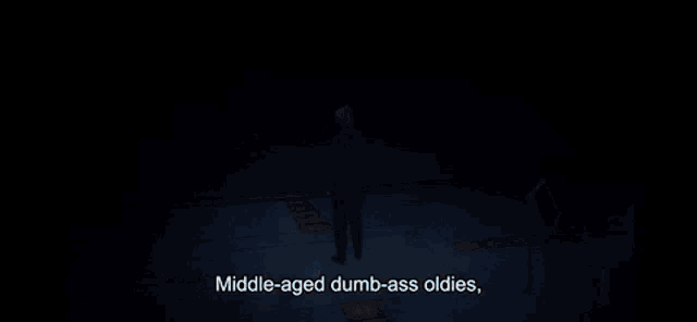 a man stands in a dark room with the words middle-aged dumb-ass oldies written below him