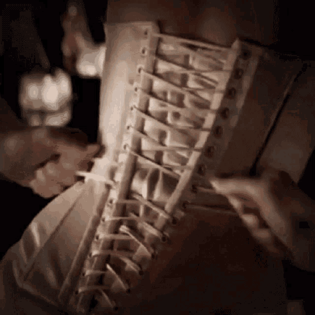 a person is tying a corset on a woman 's waist .