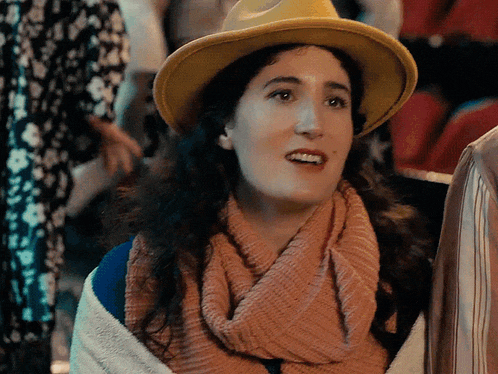 a woman wearing a yellow hat and a scarf smiles