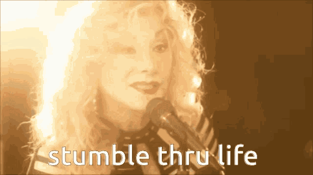 a woman singing into a microphone with the words stumble thru life
