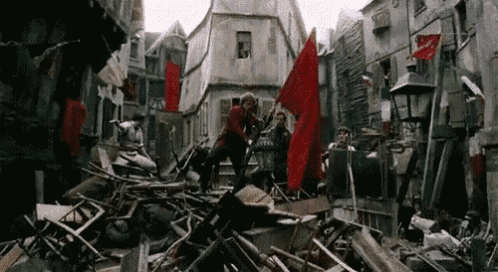 a group of people are standing on top of a pile of rubble in a city .