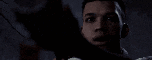 a man is holding a gun in a dark room and looking at the camera .