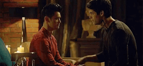 a man is touching another man 's face while sitting at a table .