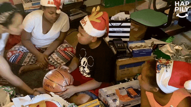 a group of people wearing santa hats are playing with a tommy brand basketball